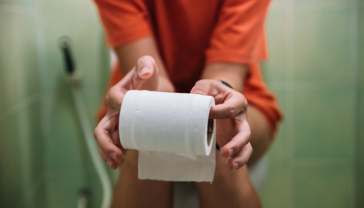Vrouw op toilet met toiletpapier in de handen